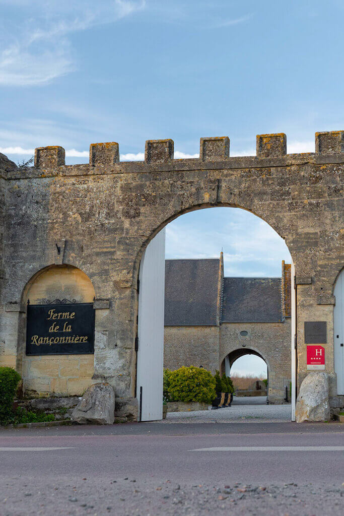 Porche d'entrée, avec ses créneaux type chateaux, de l'hotel de charme Ferme de la Ranconniere en Normandie