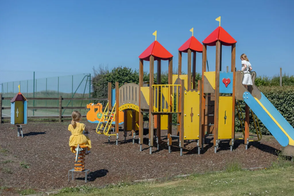 Des enfants s'amusent dans l'aire de jeux de l'hotel Ferme de la Ranconniere kid friendly en Normandie